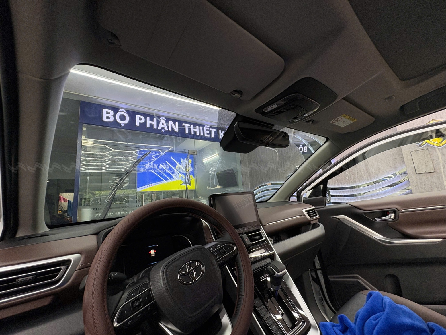 T&agrave;i xế đang l&aacute;i xe với k&iacute;nh l&aacute;i được d&aacute;n phim c&aacute;ch nhiệt 3M, khung cảnh b&ecirc;n ngo&agrave;i r&otilde; r&agrave;ng v&agrave; &aacute;nh nắng dịu nhẹ.